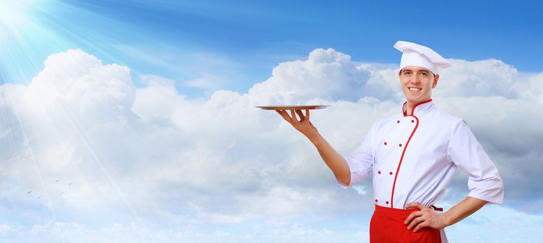 Portrait of a young male cook in red apron against colour background