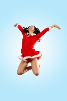 Happy smiling woman in red xmas costume jumping high