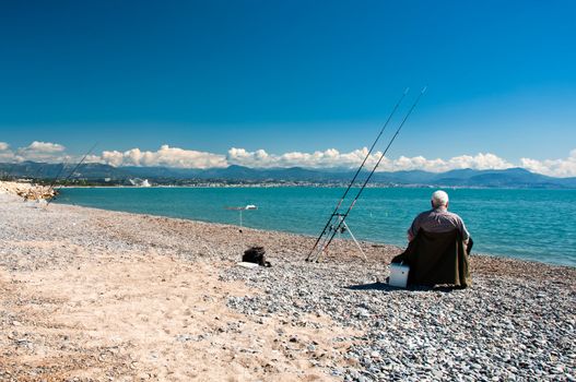 Senior fisherman at blue sea coast during sunny day, blue sky and white clouds