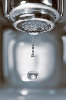 Water drop falling form a faucet in a bathroom, low depth of field