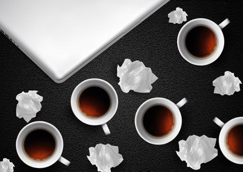 Crumpled colorful papers with laptop and coffee on black desktop.