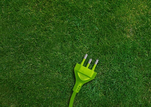 Green energy concept, Green power plug on a green grassland.