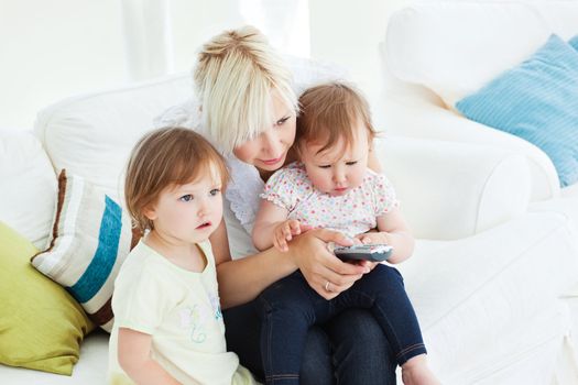 happy woman using a remote with her girl in the living-room at home
