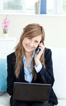 Beautiful confident businesswoman using a mobile phone and a laptop in the office