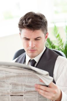 Concentrated businessman reading a newspaper sitting in his office