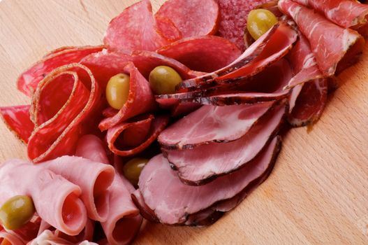 Slices of Delicatessen with Ham, Pepperoni, Chorizo and Olives closeup on Cutting Board