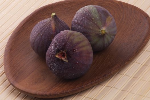 Three Perfect Ripe Figs Full Body with Droplets on Wooden Plate 