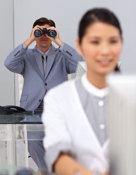 Visionary businessman using binoculars with his colleague working in the foreground