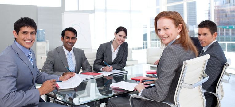 Business group showing ethnic diversity smiling at the camera in a meeting