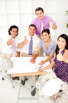 A group of architects with thumbs up in a meeting. Concept of success.