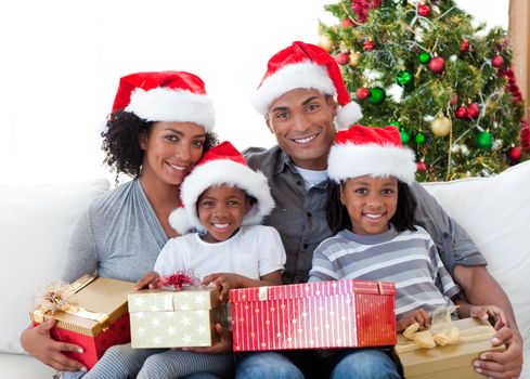 Afro-American family holding Christmas presents at home
