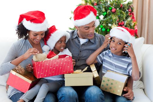 Happy Afro-American family playing with Christmas presents at home