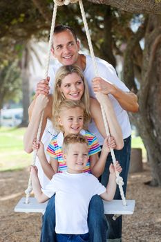 Cheerful family swinging in a park
