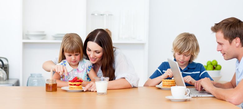 Happy family eating breakfast in the kitchen at home