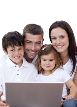 Portrait of happy young family using a laptop at home