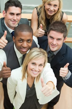 High view of happy business team with thumbs up and smiling at the camera