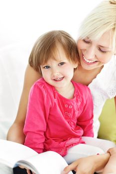 Smiling mother reading a book with children on sofa