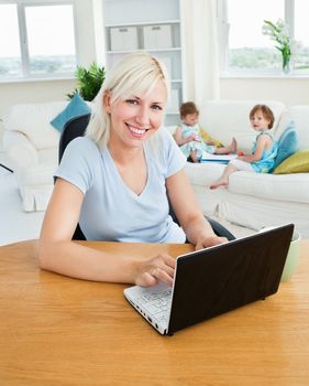 Blond mother using laptop in living room