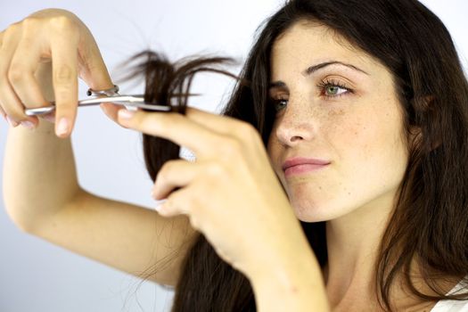 Gorgeous female model cutting her long beautiful silky hair