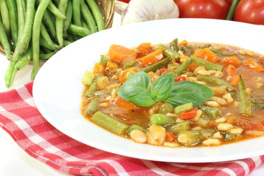 Minestrone with green beans, carrots, potatoes, leeks and garlic on a bright background