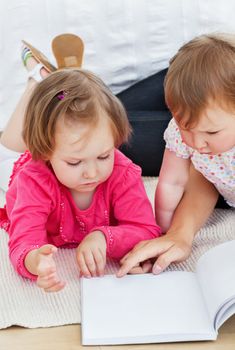 Concentrated children reading a book with their mother at home