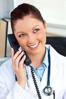 Delighted female doctor talking on phone in her office