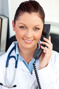 Smiling female doctor talking on phone in her office