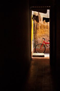 A red bicycle at the end of a hall next to a yellow wall.