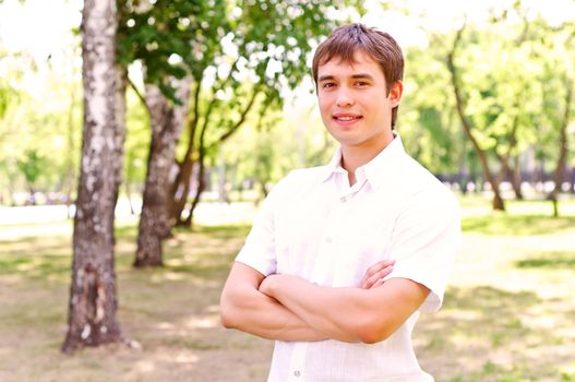 Portrait of man outside in park, crossed his arms