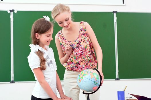 teacher explains the lesson in geography, stand near the school globe