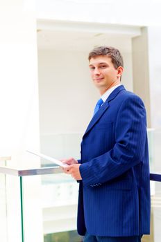 Smiling business man on the balcony, holdings reports