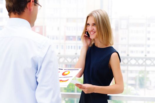 business male and business female discuss reports, Woman talking on cell phone