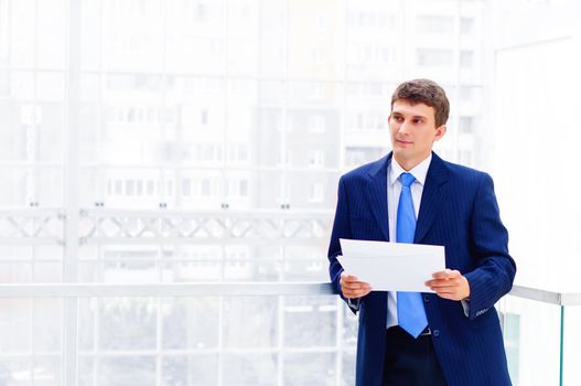 Smiling business man on the balcony, holdings reports