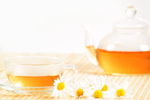 A teacup and a teapot with herbal chamomile tea