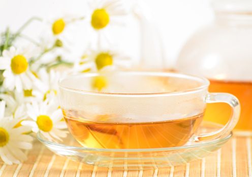 A teacup and a teapot with herbal chamomile tea