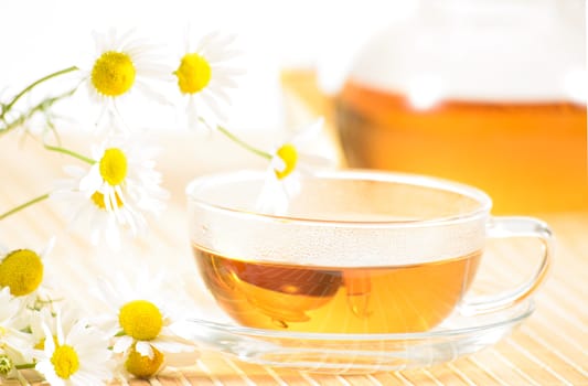 A teacup and a teapot with herbal chamomile tea