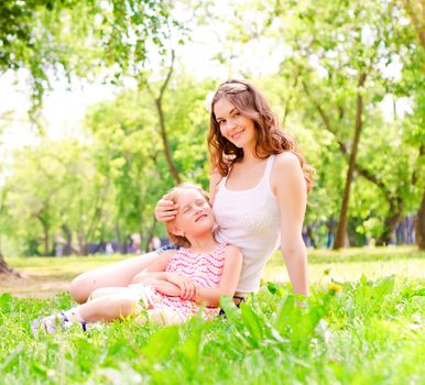 mother and daughter sitting together on the grass, and spend time with family