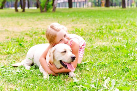 girl and she lablador, hugging in the park lying on the grass