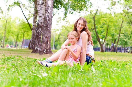 mother and daughter sitting together on the grass, and spend time with family