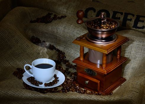 Coffee Mill with beans, cup and burlap. still life