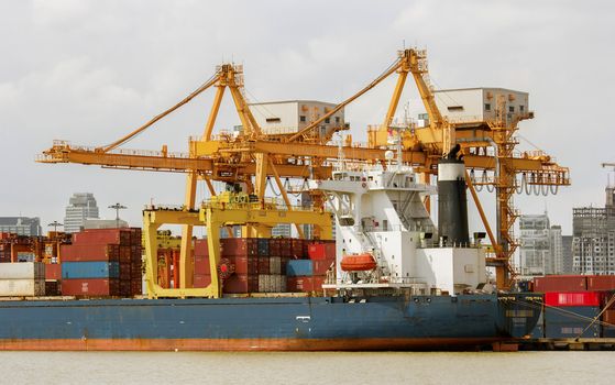 Industrial Container Cargo freight ship with working crane bridge in shipyard at dusk for Logistic Import Export background