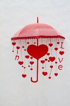 Red heart and umbrella on white wall