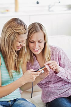 Two close female friends using a digital camera on a sofa at home