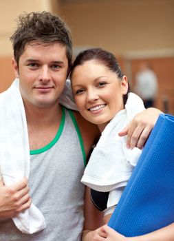 Couple of athletic people smiling at the camera in a fitness center