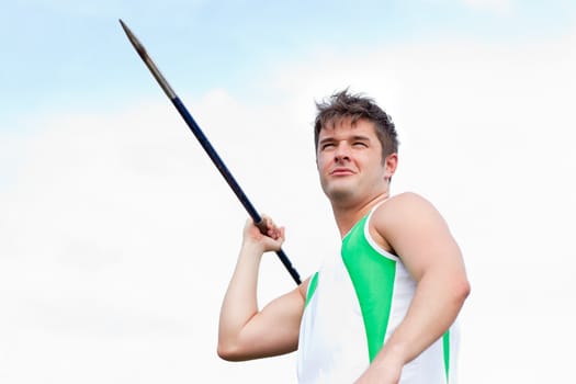 Handsome male throwing a javelin outdoors in a stadium
