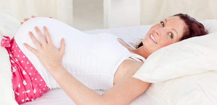 Radiant pregnant woman resting n her bed in the bedroom at home
