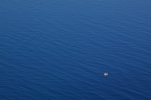 Bird's eye view of blue arctic sea with tiny norwegian fishing boat