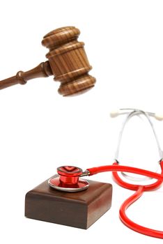 A gavel is about to hammer down on a stethoscope that is resting on the sounding block.