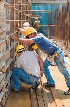 Authentic construction builders working together for positioning concrete formwork frames in place