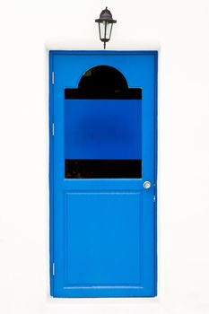 Blue door and wall lamp on white house